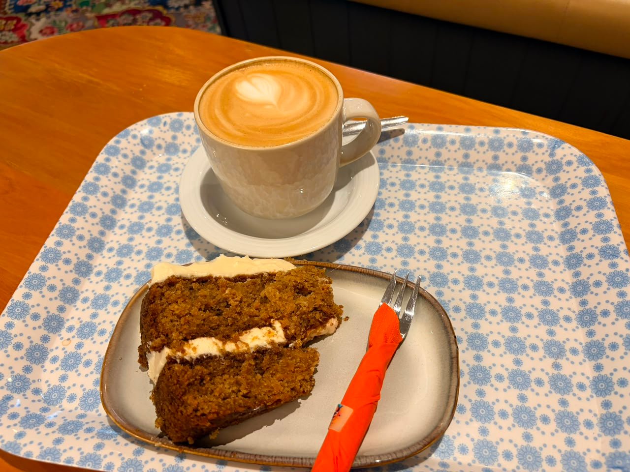 A cappuccino and a slice of wortelkoek on a wooden tray