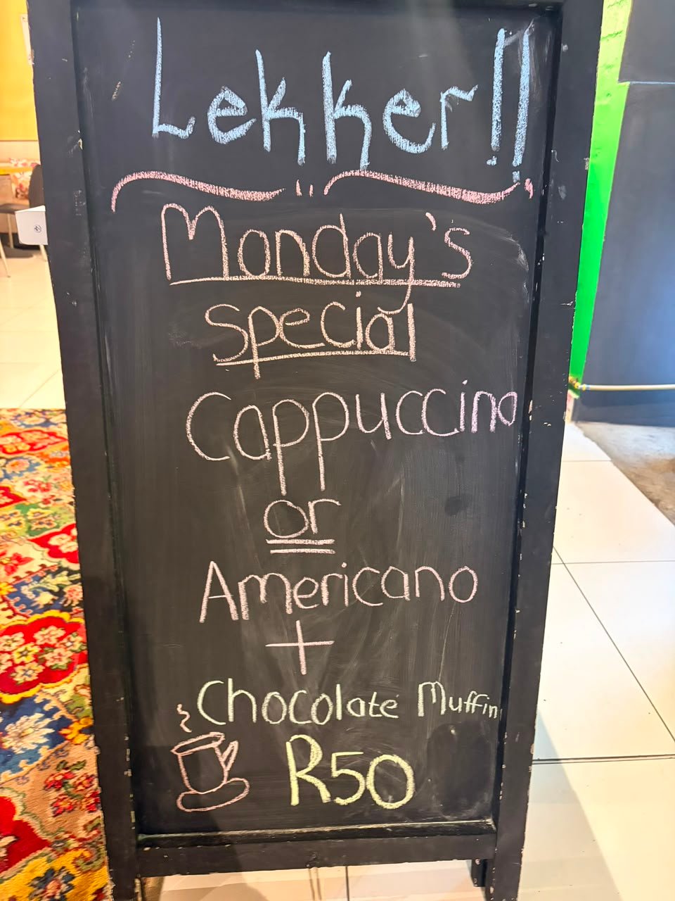 Chalkboard reading: Lekker!! Monday's special — cappuccino or americano plus a chocolate muffin, R50